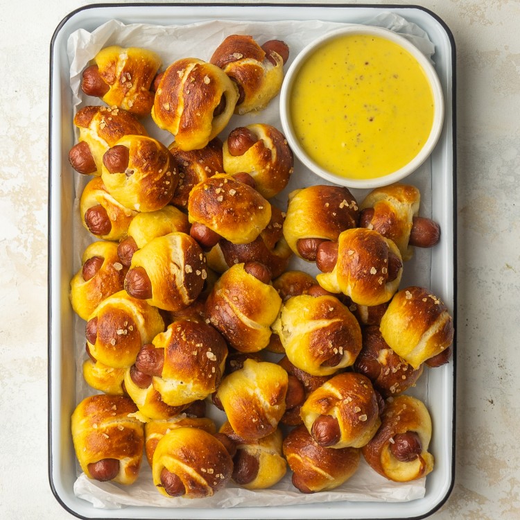Above view of mini hot dogs with a pretzel hot dog bun on a serving platter