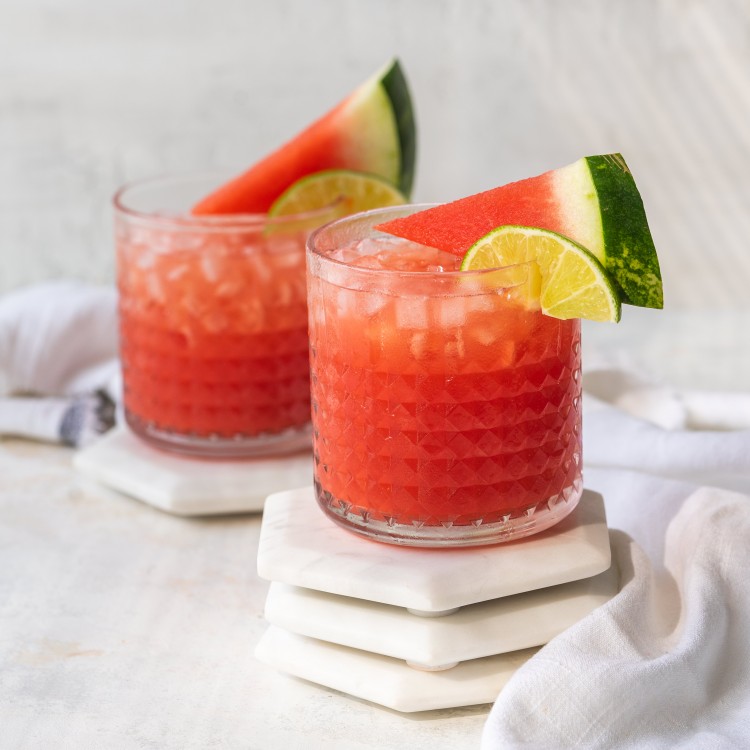 Two watermelon vodka cocktails with watermelon and lime garnish