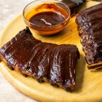 Three quarter view of air fryer ribs with bbq sauce on top