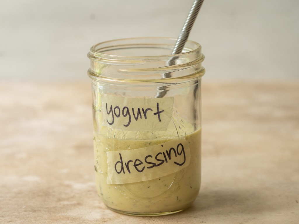 Side view of yogurt dressing in a mason jar with a whisk in it