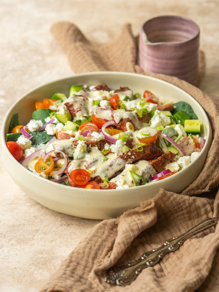 Three quarter view of a salad topped with a Greek yogurt salad dressing