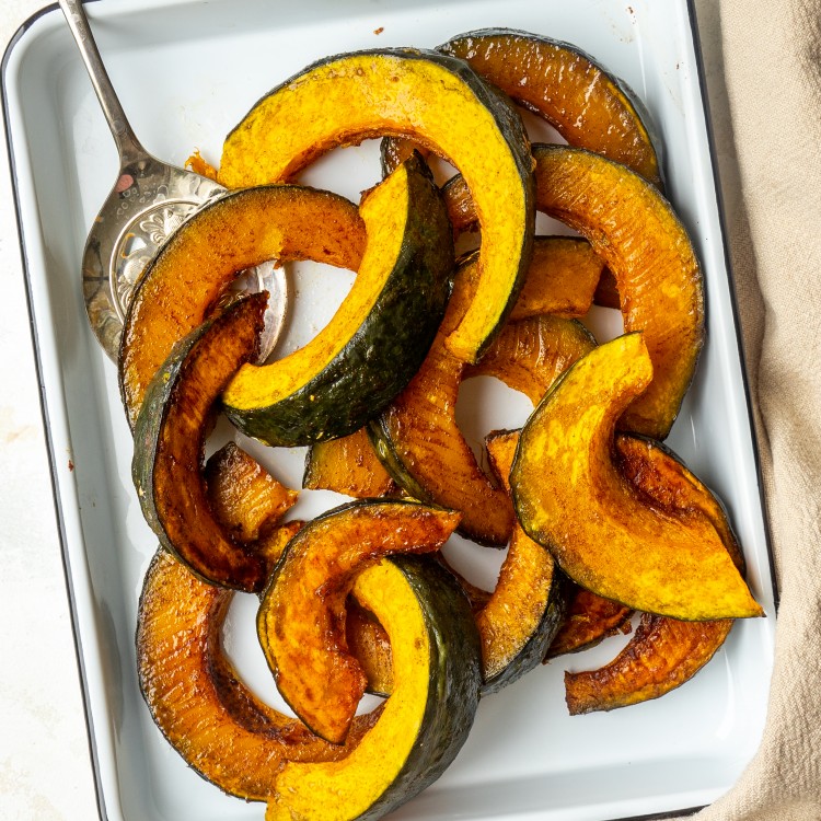 Maple cinnamon roasted kabocha squash recipe on a serving platter with a serving spoon