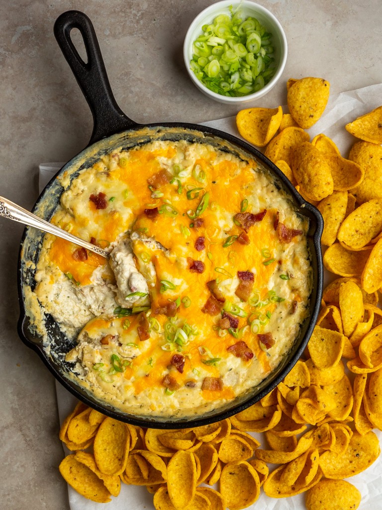 Above view of a chicken cheese dip recipe in a cast iron skillet with chips next to it