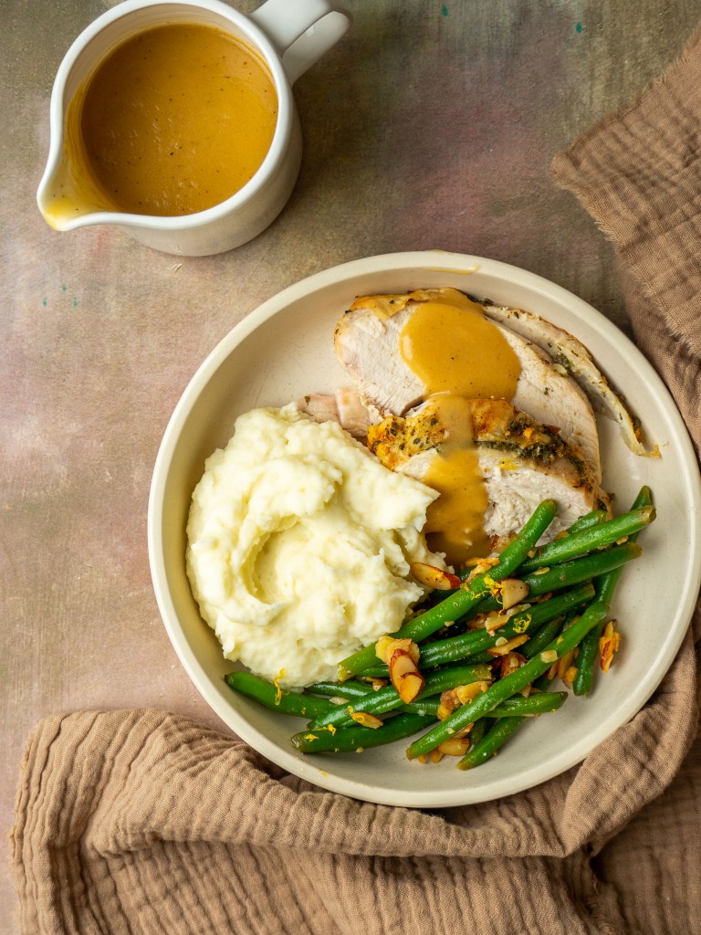 Above view of roast turkey breast with gravy, mashed potatoes and green beans