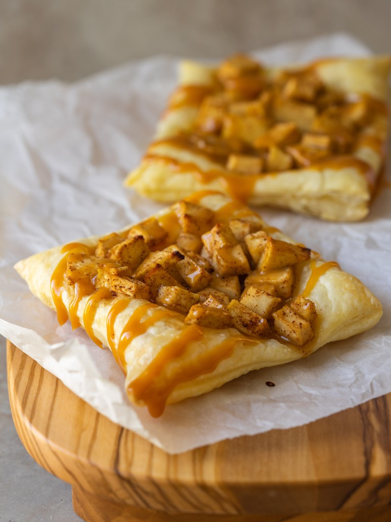 Three quarter view of puff pastry apple tart on a serving platter with caramel sauce on top