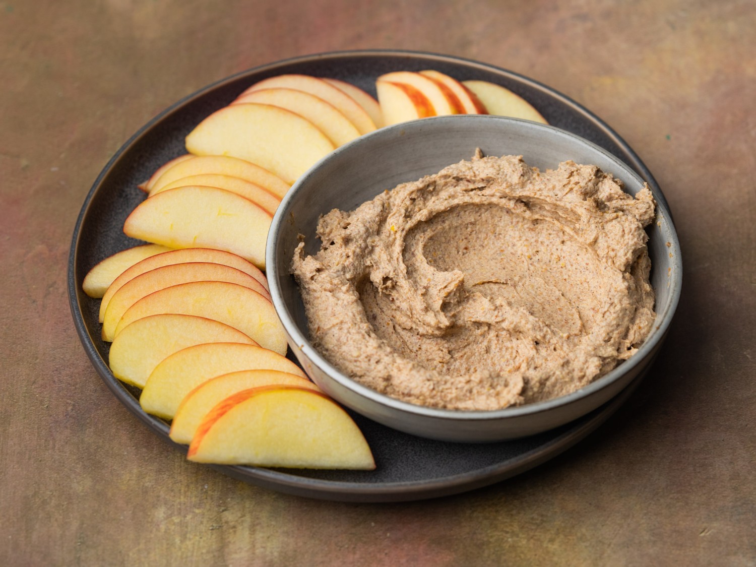 Three quarter view of peanut butter dip with sliced apples