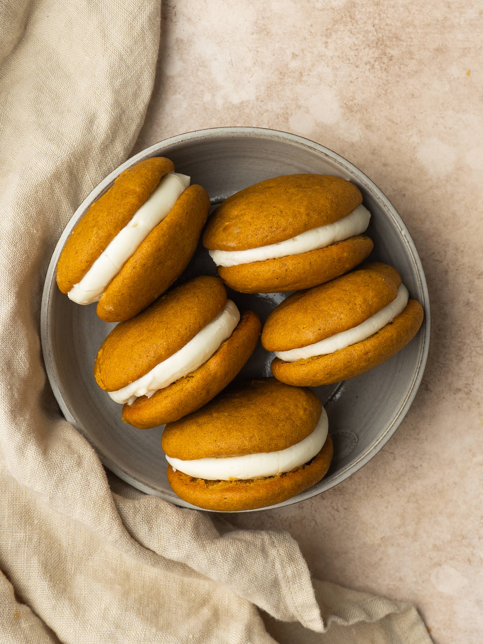 Above view of pumpkin whoopie pies with cream cheese filling in a little bowl