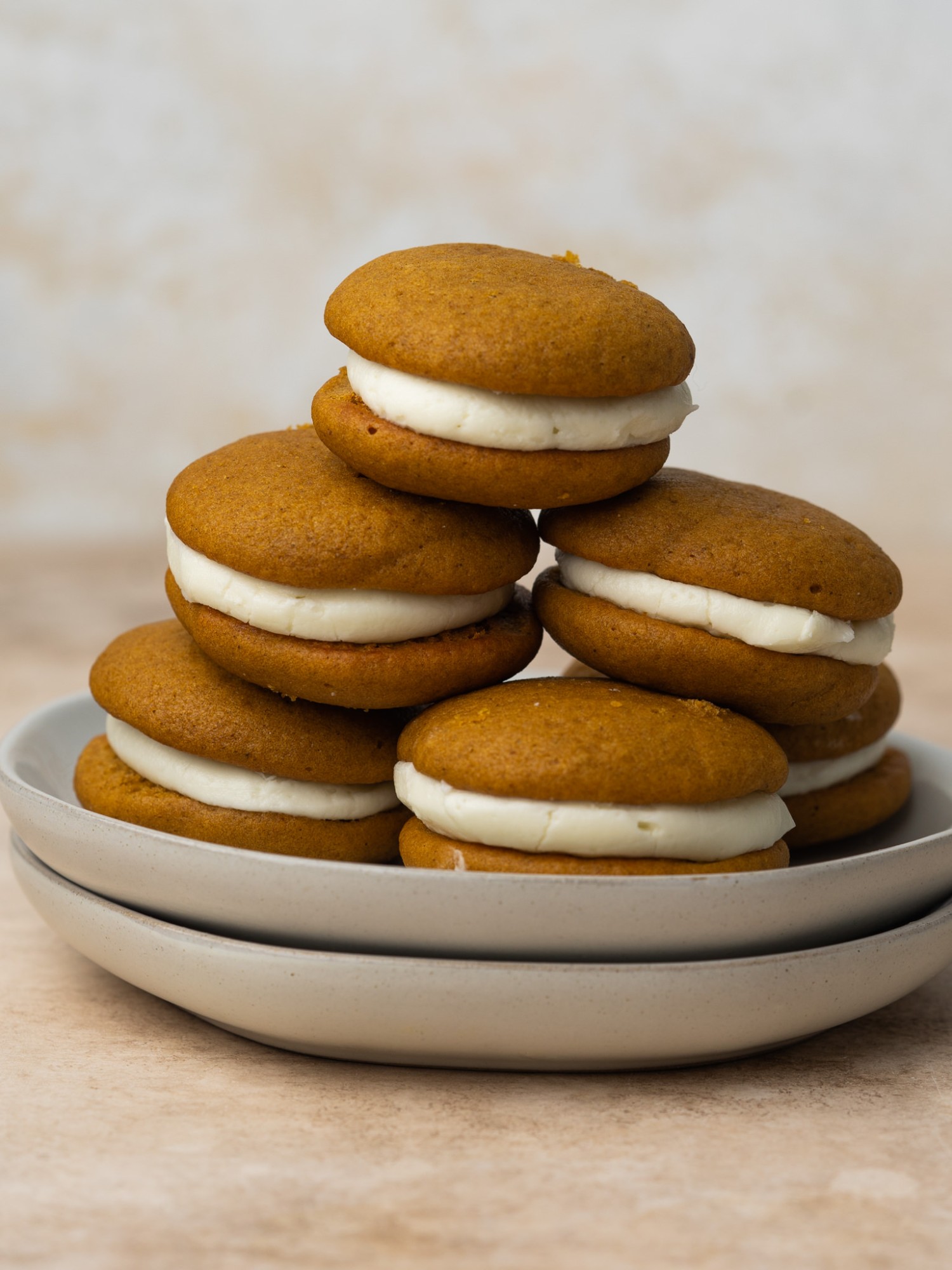 pumpkin whoopie pies stacked up on a plate