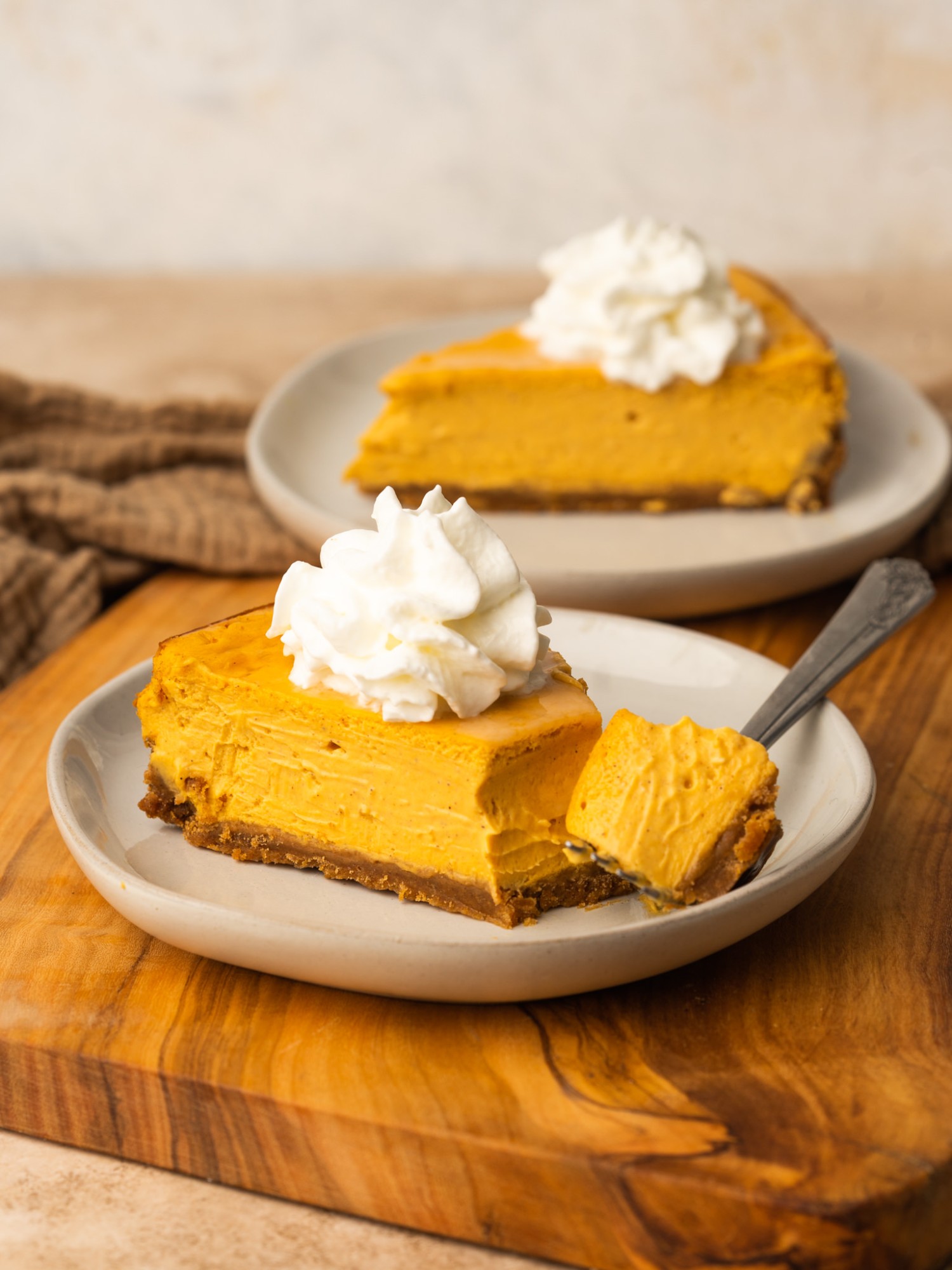 Three quarter view of two slices of sweet potato cheesecake served with whipped cream