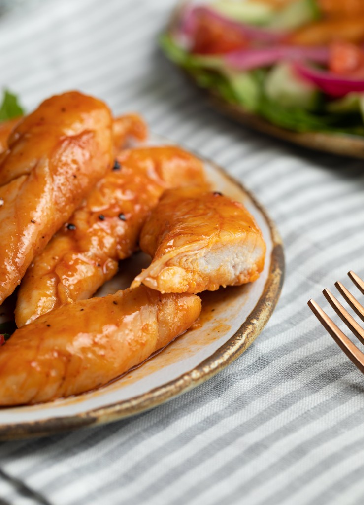 Close up three quarter view of honey sriracha chicken on a serving plate