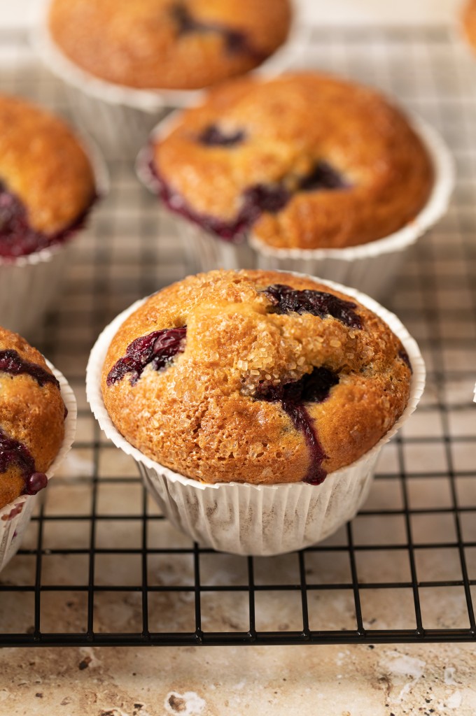 Close up view of a blueberry yogurt muffin on a cooling rack