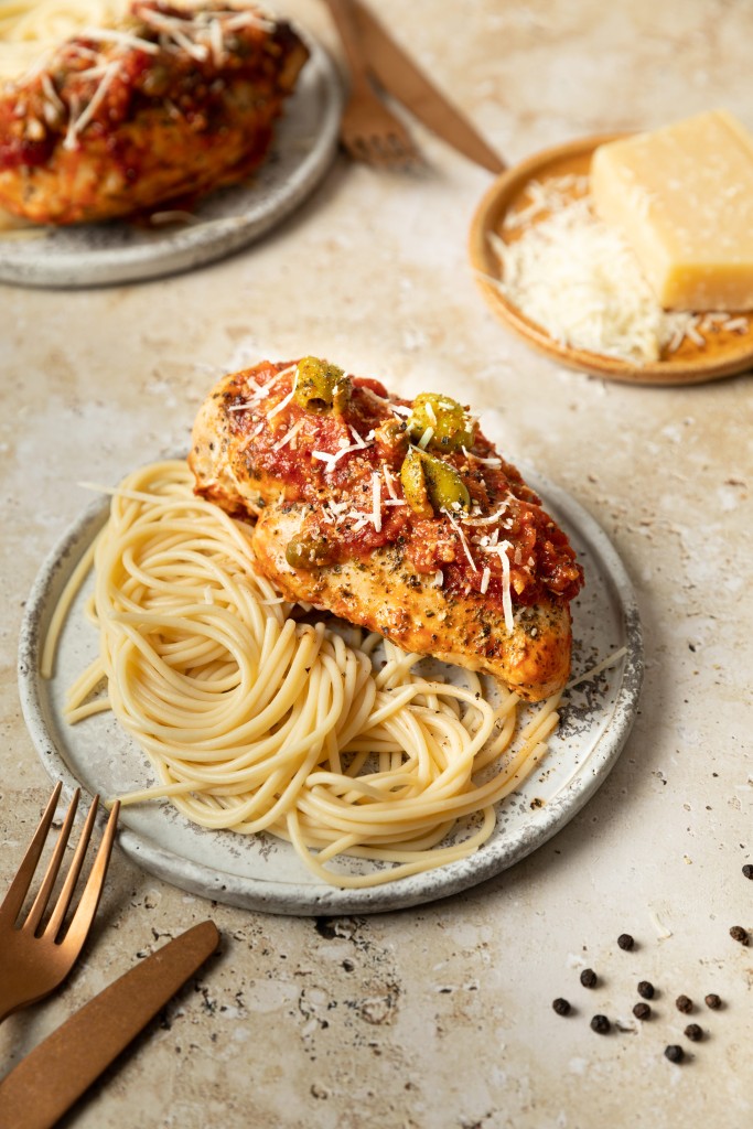 Three quarter view of a chicken puttanesca recipe served with pasta