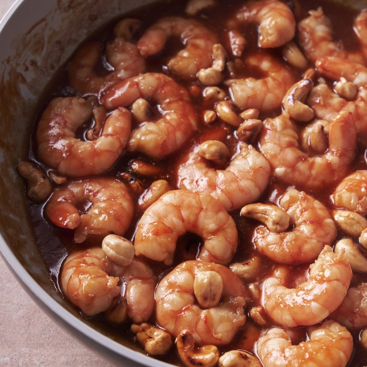 Above view of sweet and sour shrimp in a pan with toasted cashews
