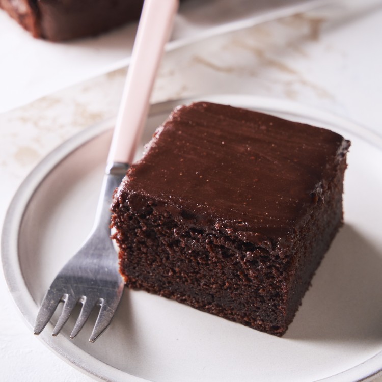 Three quarter view of a slice of ganache cake with a fork next to it