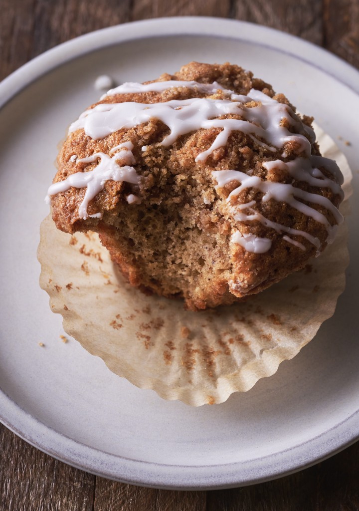Coffee cake muffin on a plate with a bite out of the side of it