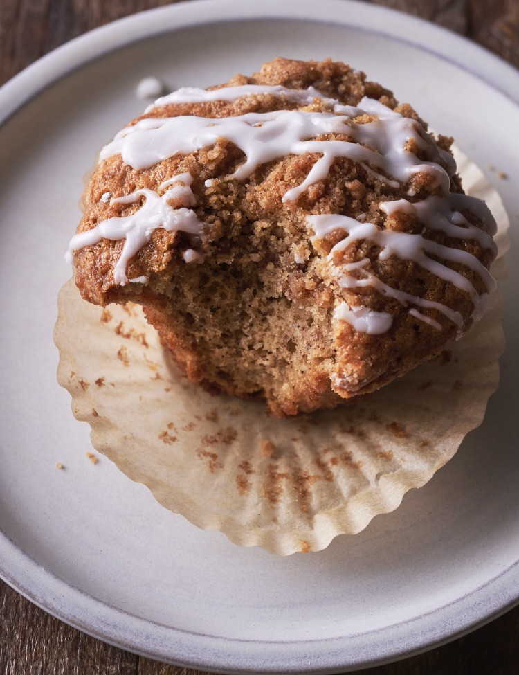 Coffee cake muffin on a plate with a bite out of the side of it