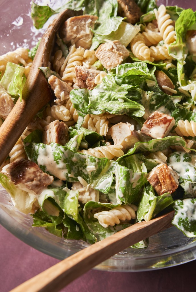 Close up above view of chicken caesar pasta salad in a mixing bowl
