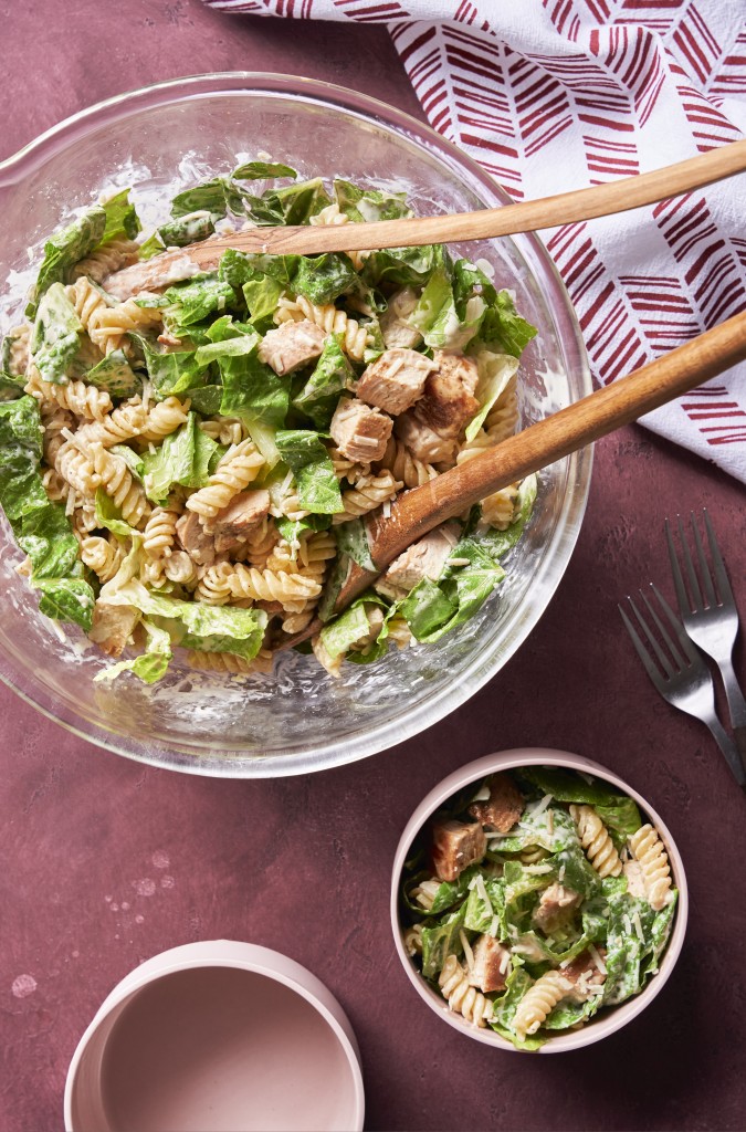 Chicken caesar pasta salad in a mixing bowl and in a serving bowl
