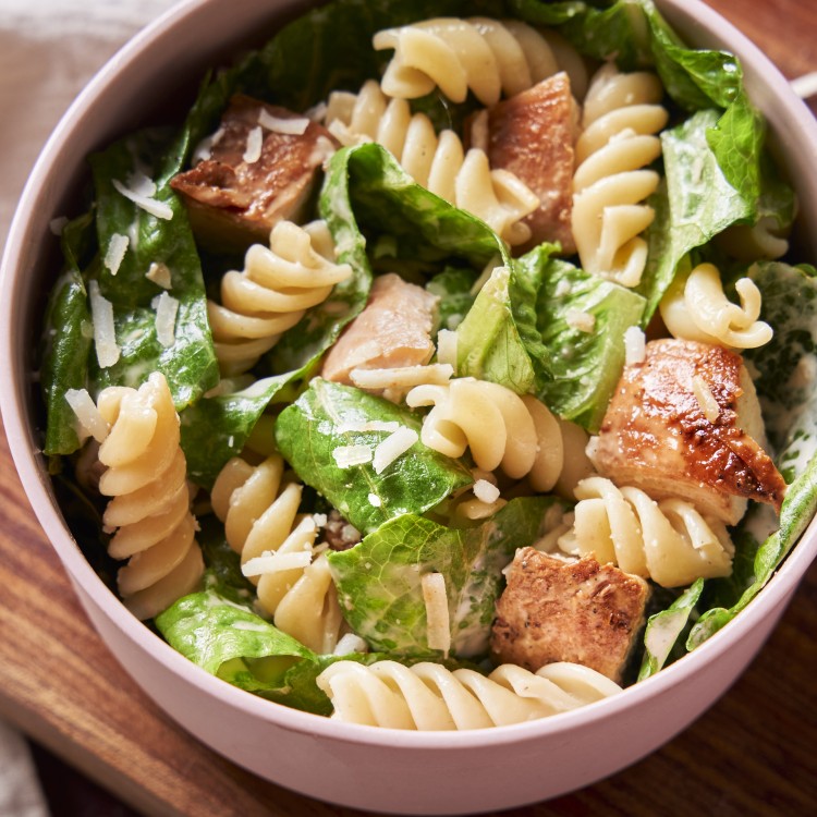 Close up above view of chicken caesar pasta salad in a serving bowl
