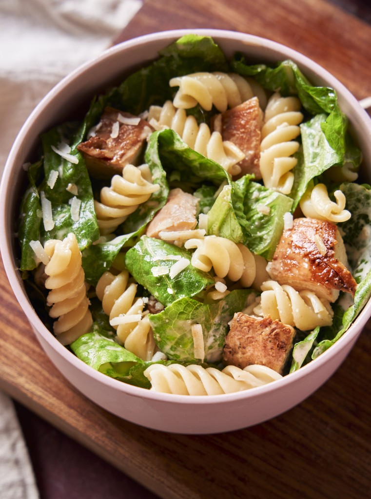 Close up above view of chicken caesar pasta salad in a serving bowl