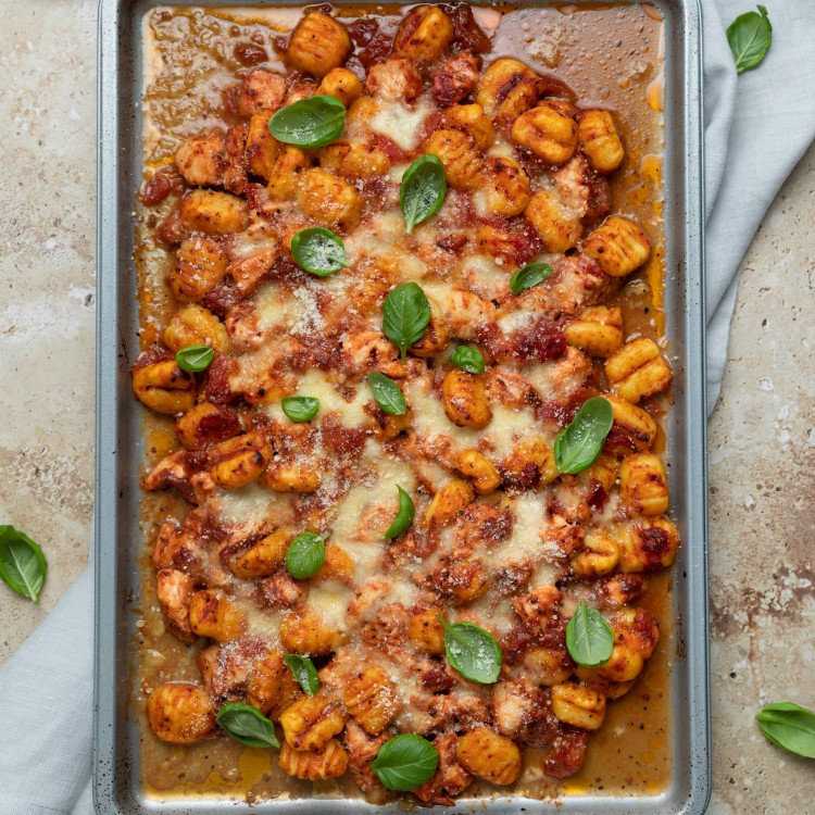 Sheet pan chicken and gnocchi from above garnished with basil