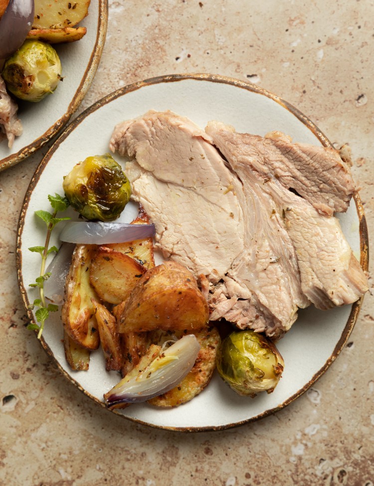 Above view of sliced instant pot pork roast on a serving plate with veggies