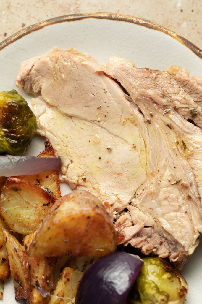 Close up above view of a slice of roast pork on a serving plate with extra juices