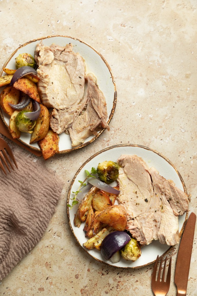 Above view of two plates of instant pot pork roast serve with roasted potatoes and brussels sprouts