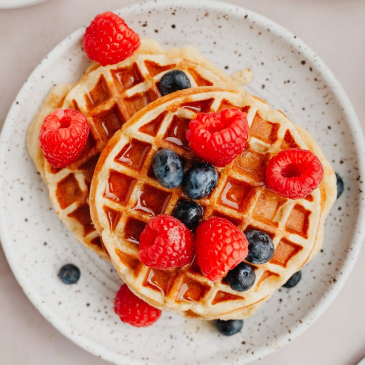 Above view of protein waffles served with fresh berries and syrup