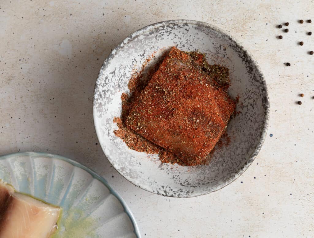 mahi mahi fillet in a bowl with blackened seasoning