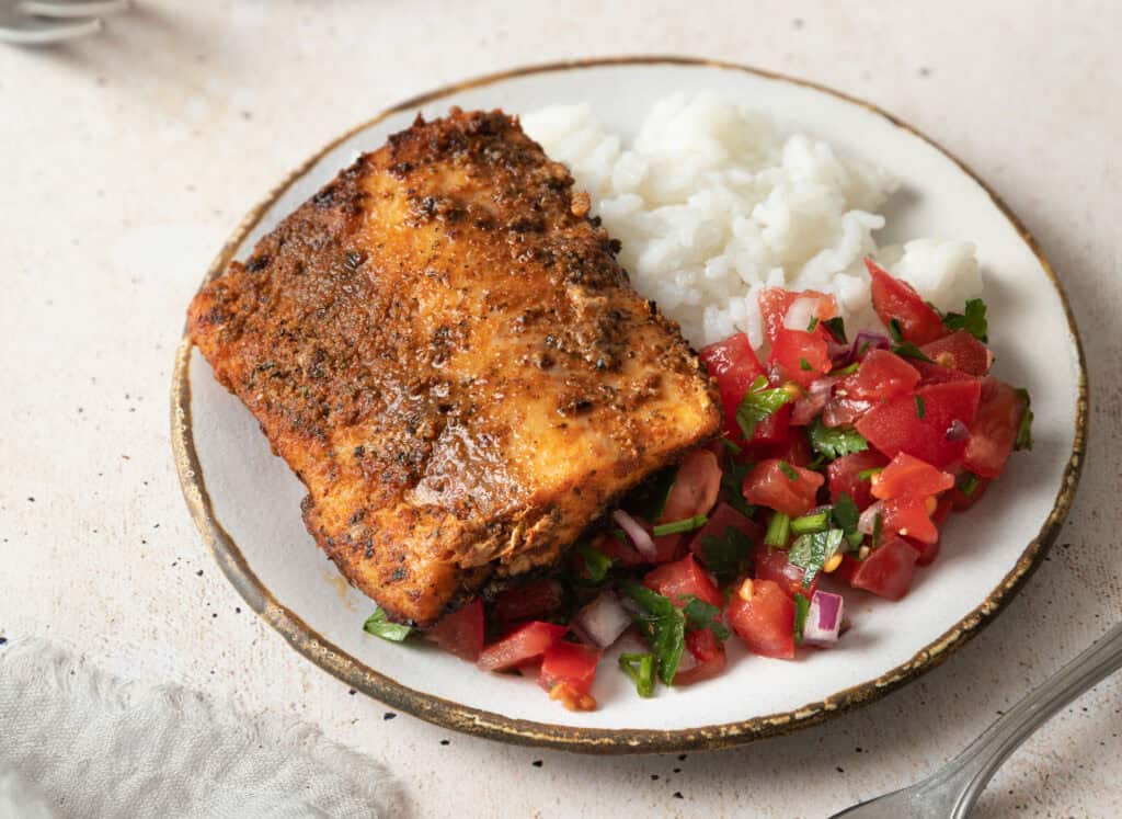 blackened mahi mahi on a plate with rice and pico de gallo