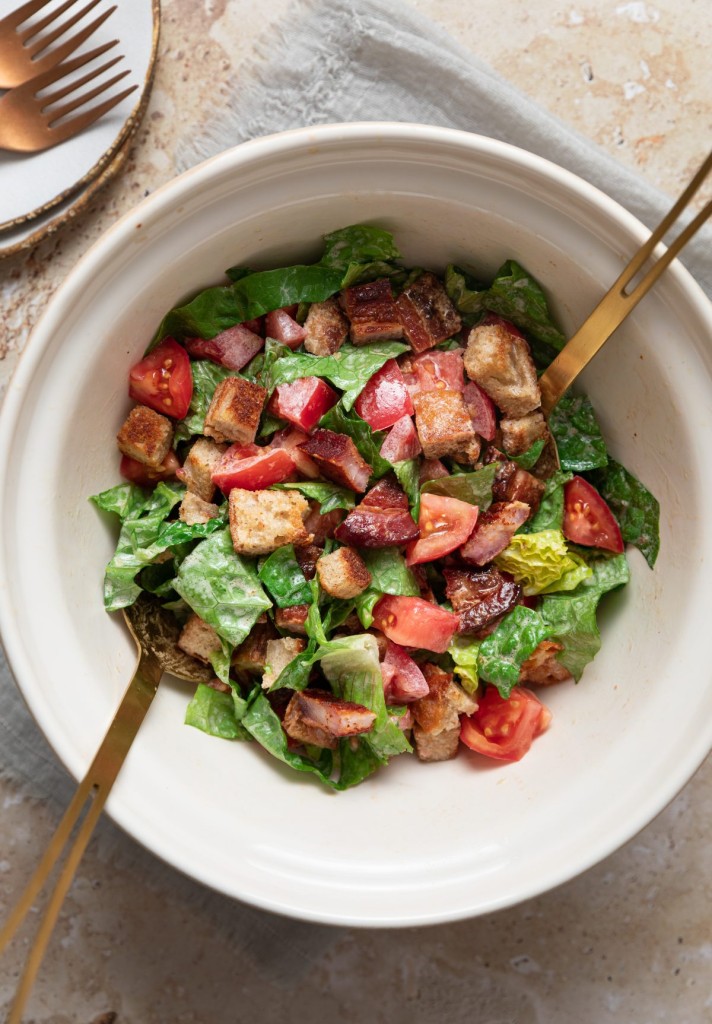 Lettuce, tomato, bacon and bread tossing in a BLT salad dressing
