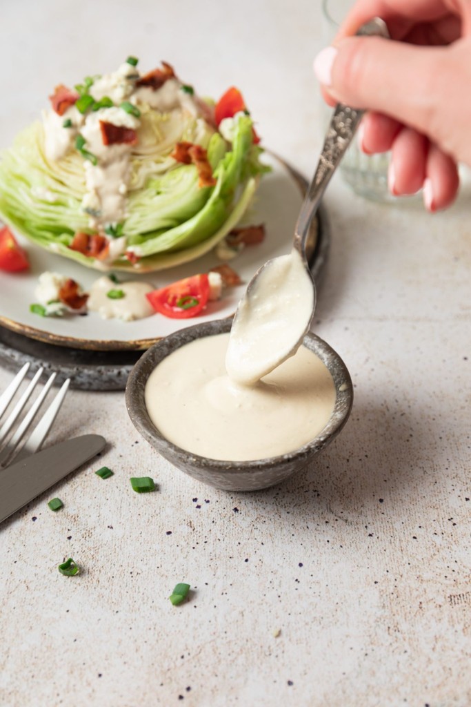 Blue cheese salad dressing being drizzled over a wedge salad