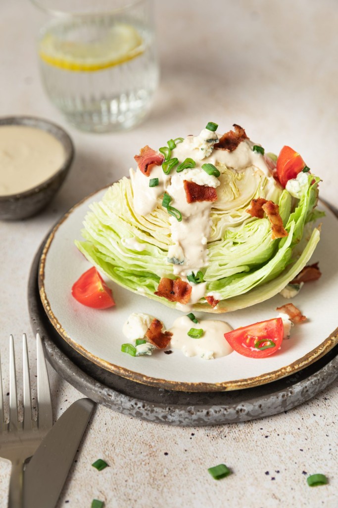 Wedge salad on a serving plate with lots of topings