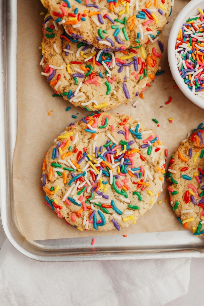 Above view of sugar cookies with sprinkles on a baking sheet