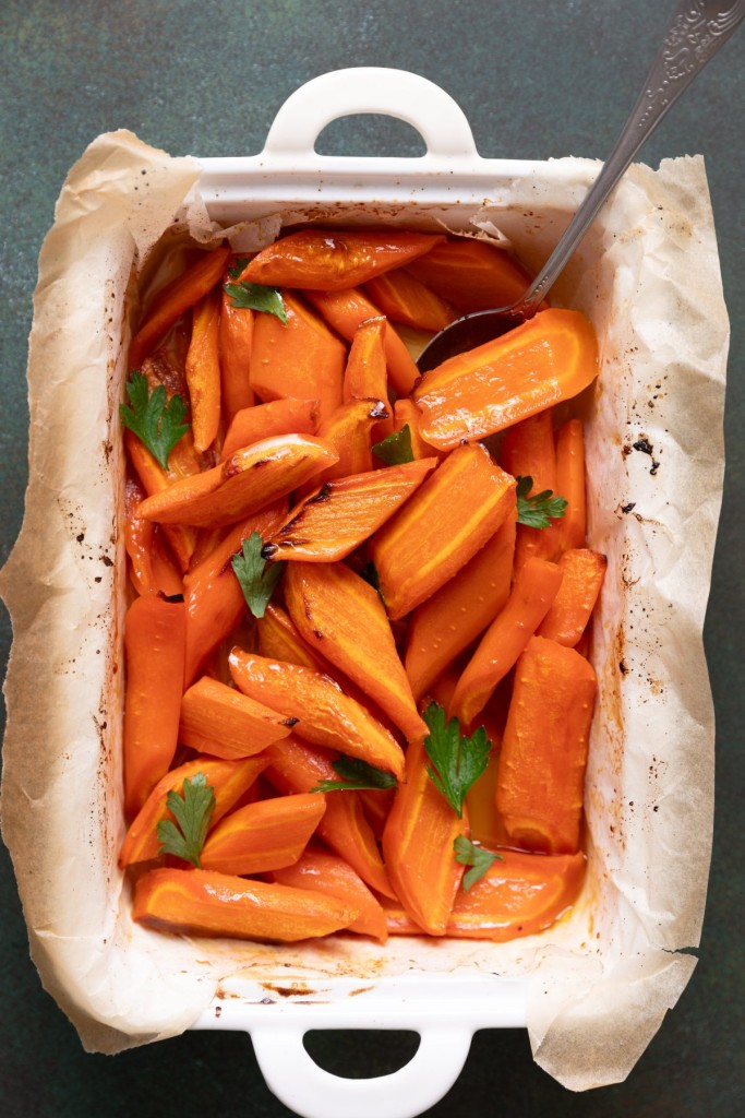 Above view of maple carrots in a casserole dish with fresh herbs