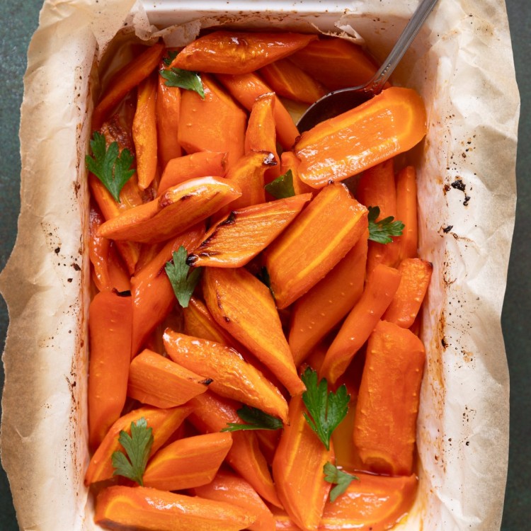 Above view of maple carrots in a casserole dish with fresh herbs