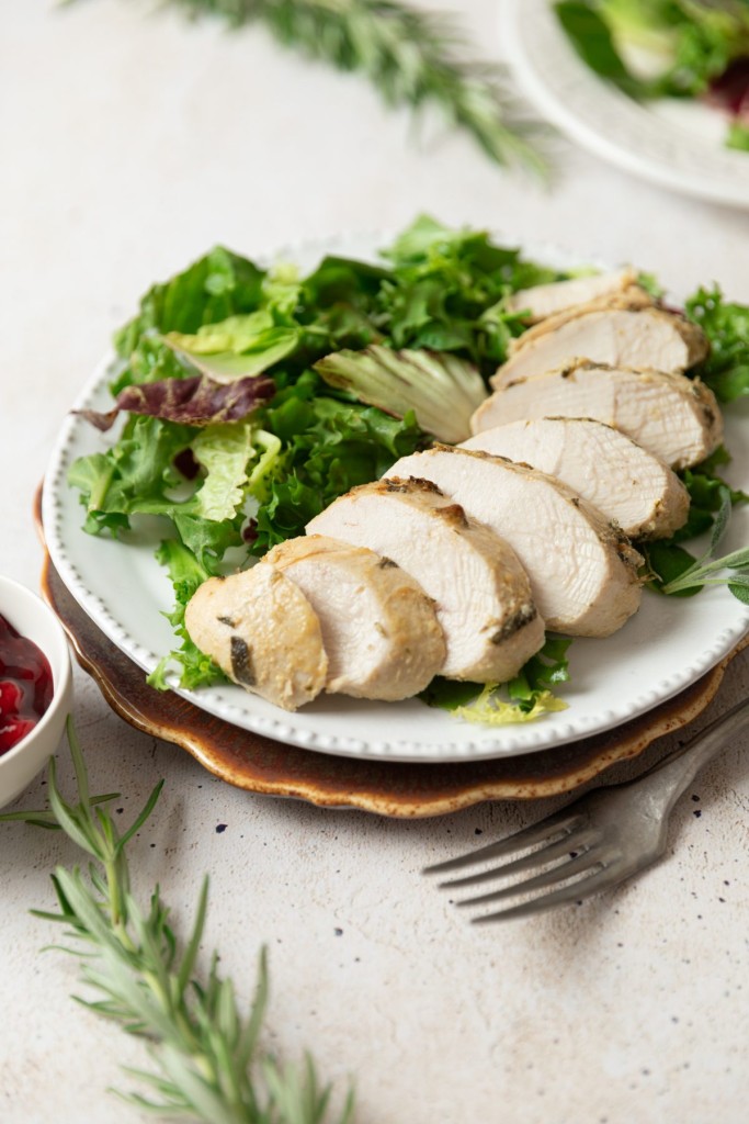 Three quarter view of sliced turkey tenderloin on a plate with a salad