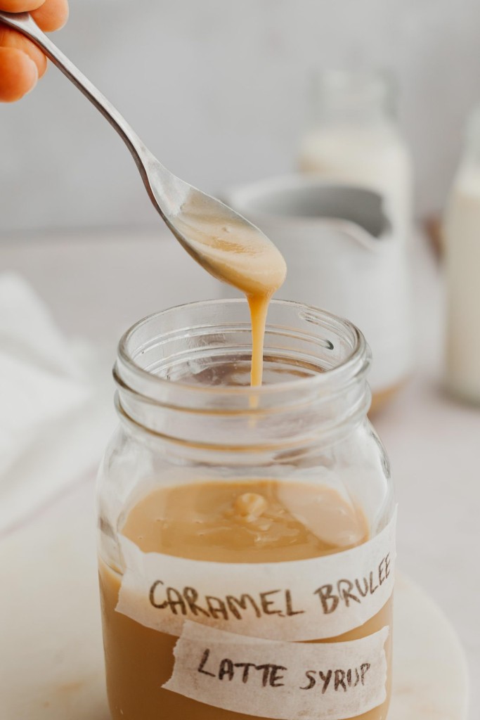 Spoon reaching into a jar of homemade caramel brulee latte syrup