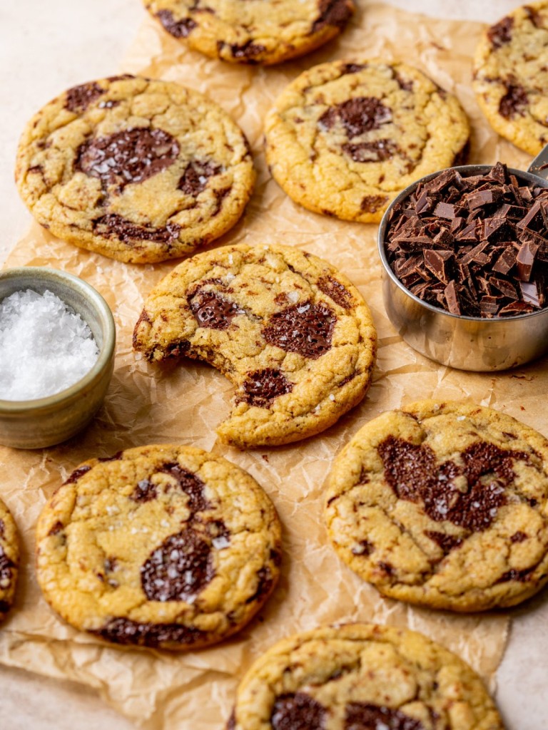Three quarter view of salted brown butter chocolate chip cookies on a piece of parchment paper