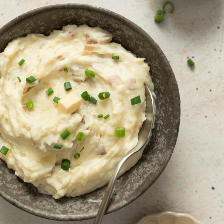 Above view of red mashed potatoes in a serving bowl with a small dollop of butter and chives