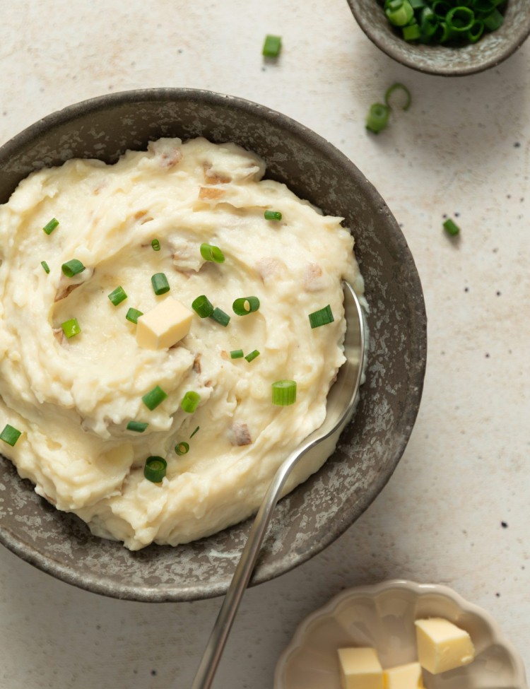 Above view of red mashed potatoes in a serving bowl with a small dollop of butter and chives
