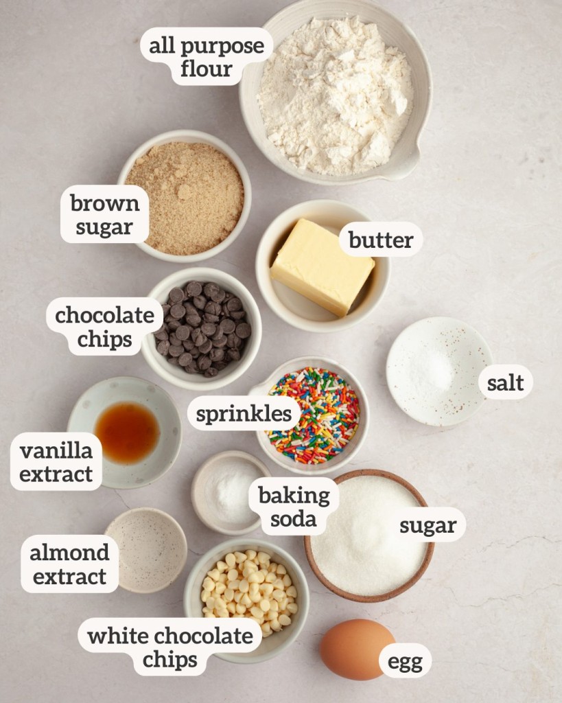 Ingredients to make birthday cake cookies arranged on a counter with labels on each ingredient