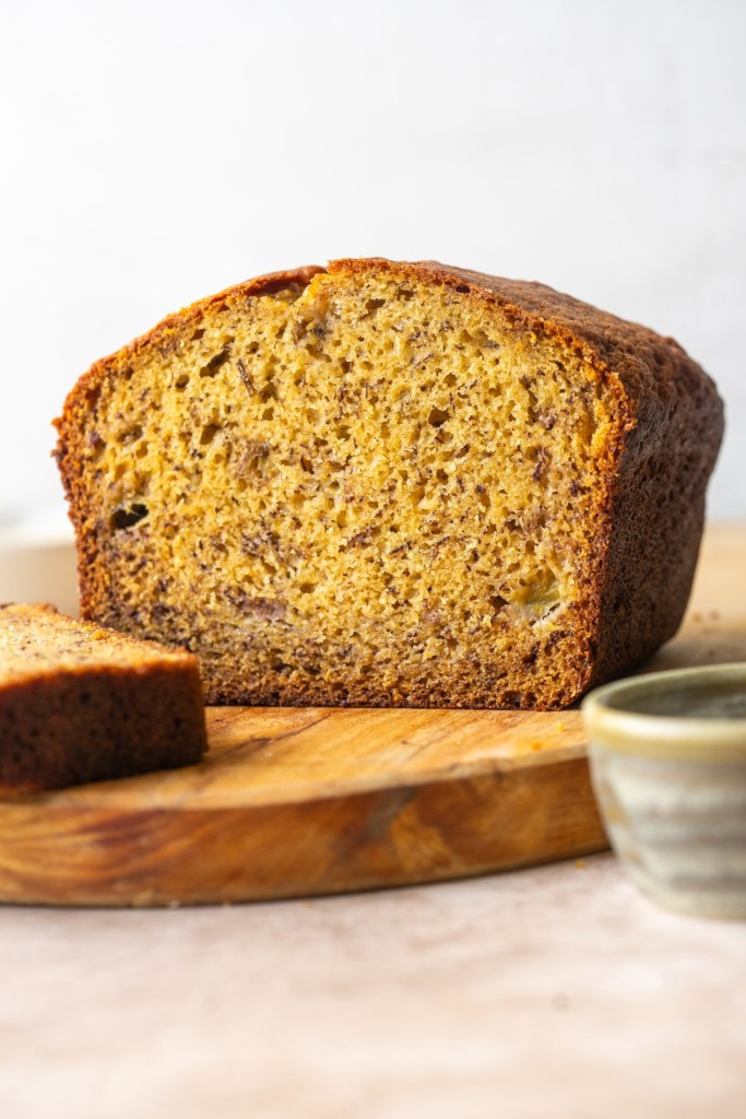 side view of a loaf of brown butter banana bread cut in half to show the inside