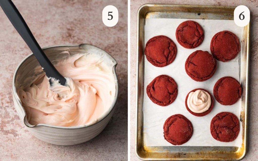 A picture of pink cream cheese frosting in a small mixing bowl next to red velvet cookies on a baking sheet with icing on one of the cookies