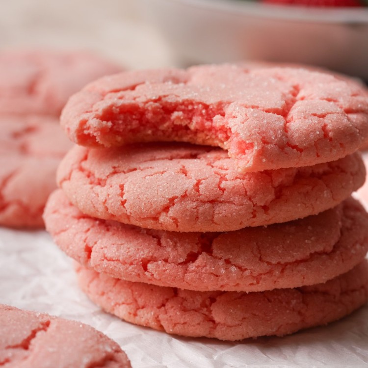 Side view of strawberry cookies stacked up with a bite out of the top cookie