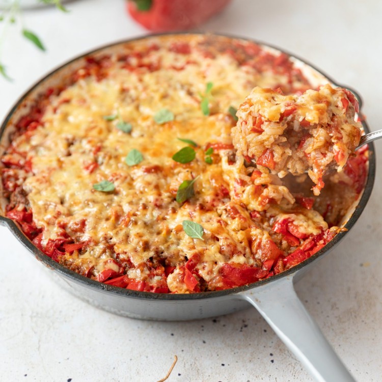 three quarter shot of stuffed pepper casserole in a white pan with a scoop on a spoon