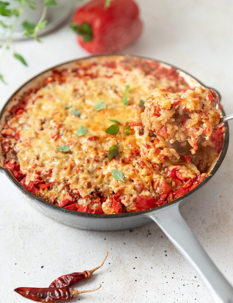 three quarter shot of stuffed pepper casserole in a white pan with a scoop on a spoon