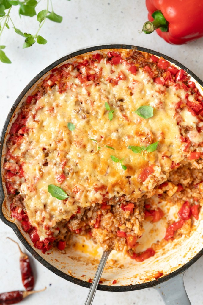 above shot of stuffed pepper casserole in a white pan with a portion cut out