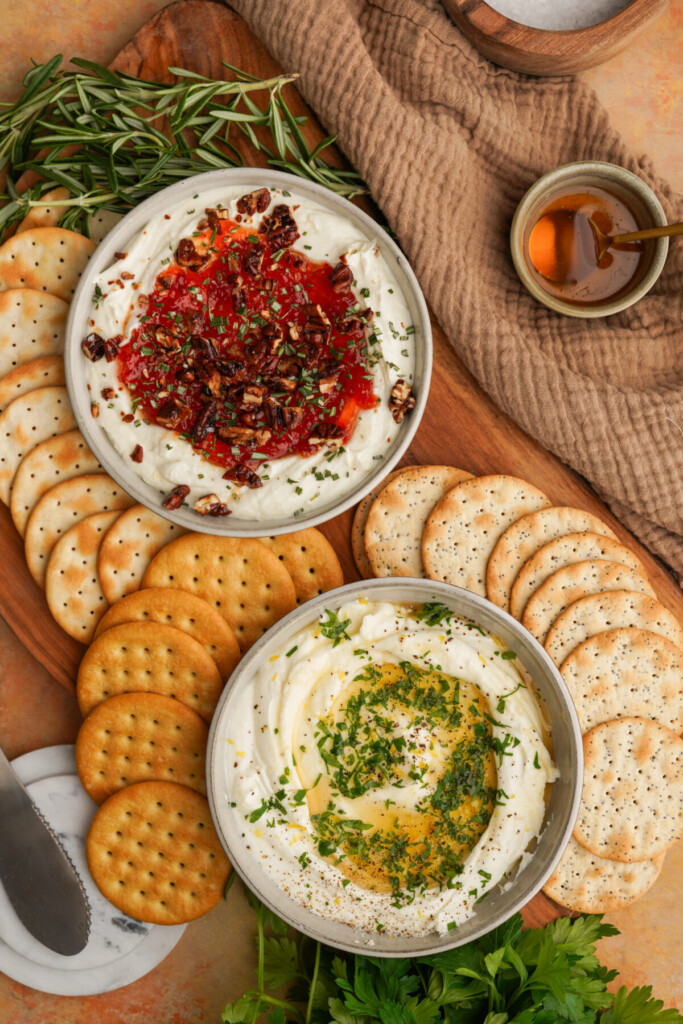 an above photo of two bowls of goat cheese dip with crackers around them on a cutting board